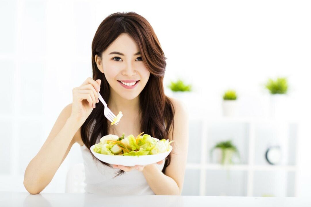Den japanska kvinnan äter en sallad
